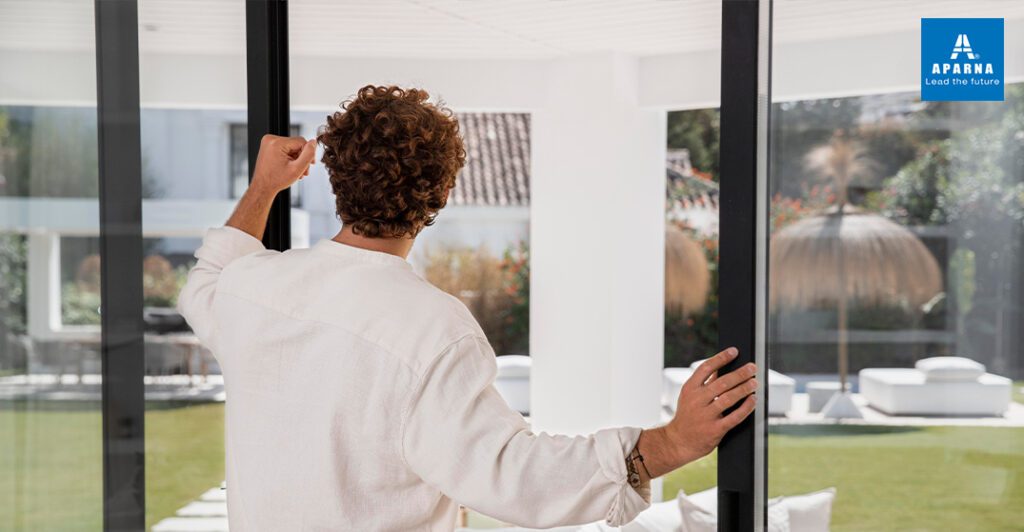 Man opening a large sliding uPVC window in a modern home by Aparna